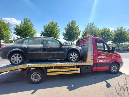 Autoturism sedan negru, murdar, încărcat pe platforma hidraulică, în parcare