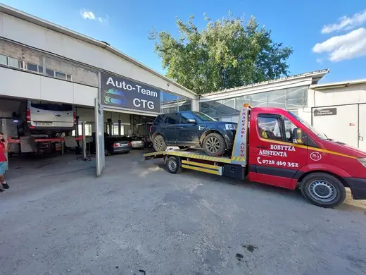 SUV negru încărcat pe platforma hidraulică, în curtea unui service auto