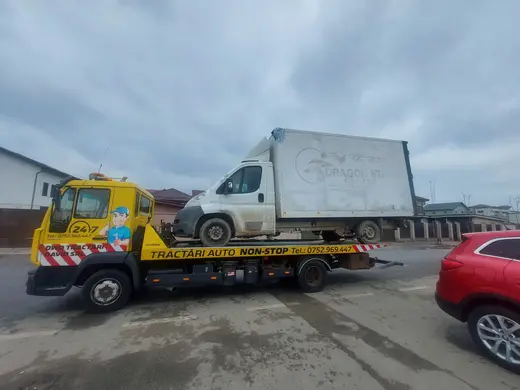 Camionetă albă cu cutie de marfă încărcată pe platforma hidraulică, ziua pe stradă