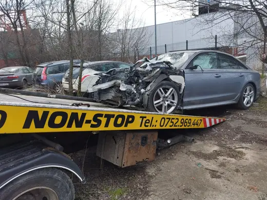 Autoturism grav avariat frontal, cu capota și farurile distruse, încărcat pe platformă