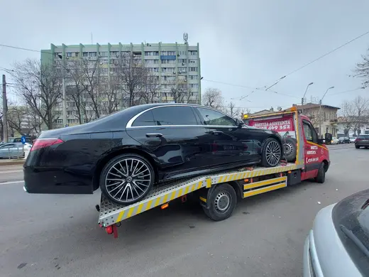 Sedan negru de lux încărcat pe platforma hidraulică, pe o stradă din oraș