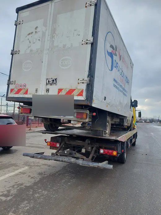 Camionetă cu cutie de marfă, văzută din spate, încărcată pe platforma hidraulică
