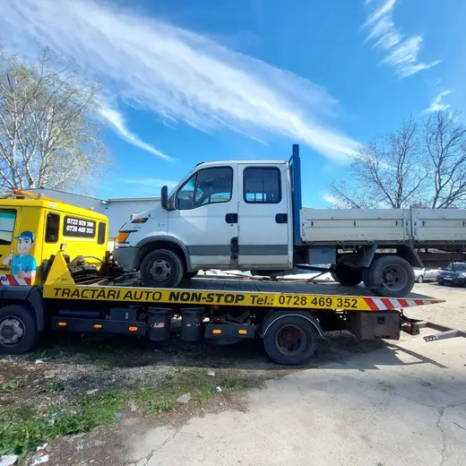 Camion alb cu basculantă goală, încărcat pe platforma mașinii de tractare