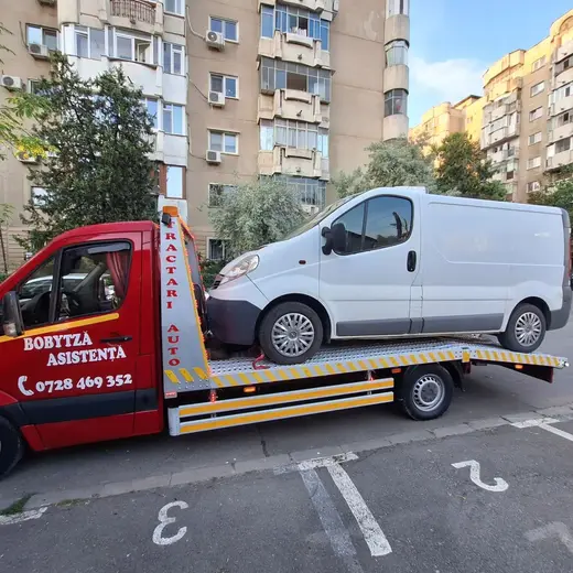 Duba albă de marfă încărcată pe platforma hidraulică, într-o parcare de bloc