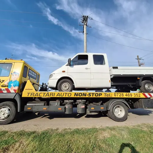 Camionetă albă cu cabină dublă, încărcată pe platforma hidraulică de tractare