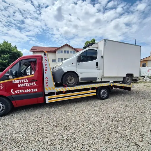 Camionetă albă cu ladă frigorifică, încărcată pe platforma hidraulică de tractare