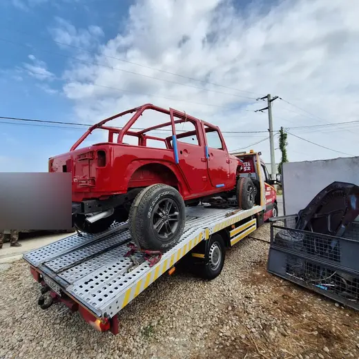 Șasiu roșu de off-road fără caroserie completă, cu cadru de protecție, pe platformă