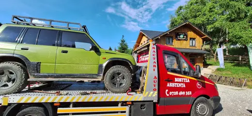 SUV verde cu portbagaj pe plafon, încărcat pe platforma hidraulică de tractare
