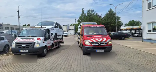Microbuz alb încărcat pe platforma hidraulică, lângă o altă mașină de tractare
