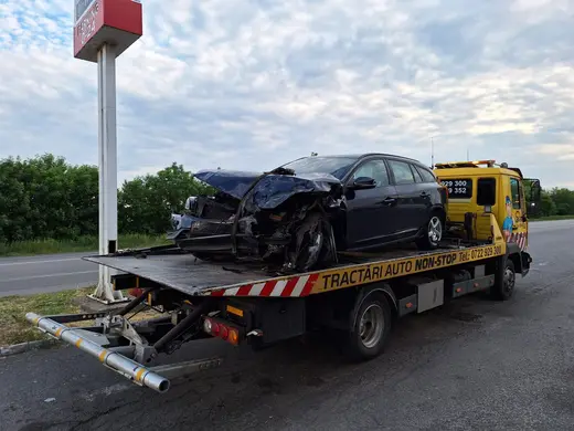 Autoturism break avariat frontal, cu caroseria deformată, încărcat pe platformă