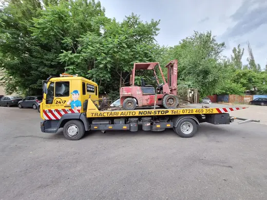 Stivuitor roșu ruginit, transportat pe platforma hidraulică a camionului de tractare