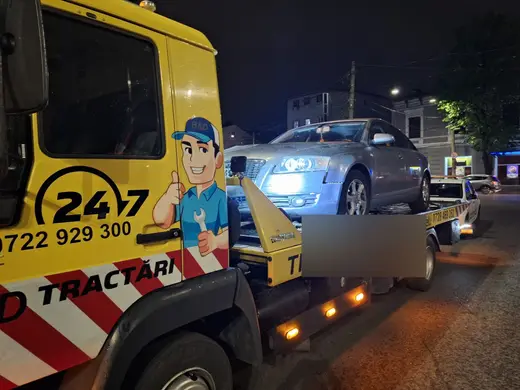 Autoturism argintiu tractat noaptea, încărcat pe platforma hidraulică a camionului