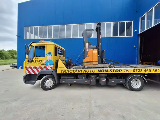 Stivuitor electric portocaliu, încărcat pe platforma camionului de tractare, ziua