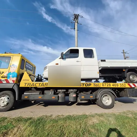 Camion basculantă alb, încărcat pe platforma unei mașini de tractare