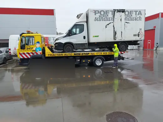 Autoturism argintiu tip break, încărcat pe platforma hidraulică a camionului de tractare