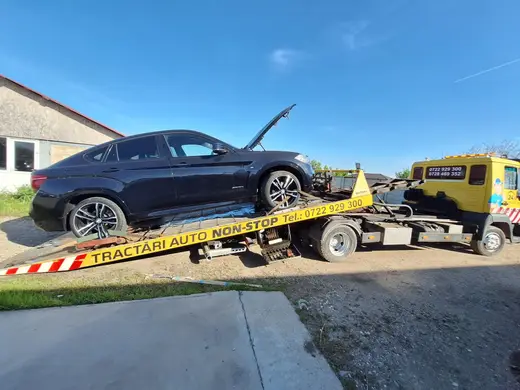 SUV coupe negru cu capota deschisă, încărcat pe platforma camionului de tractare